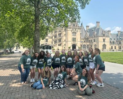 Singers gathered under a shade tree in front of Biltmore Estate