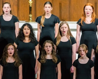 Singers in concert black performing in front of a wooden chancel