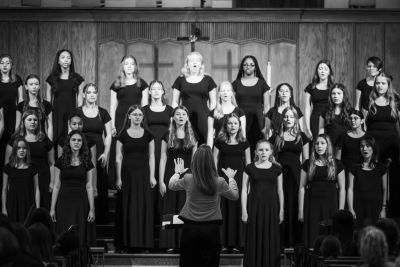 Black-and-white view of the full choir with the conductor seen from behind
