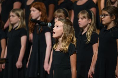 A soloist singing at the microphone in front of the choir