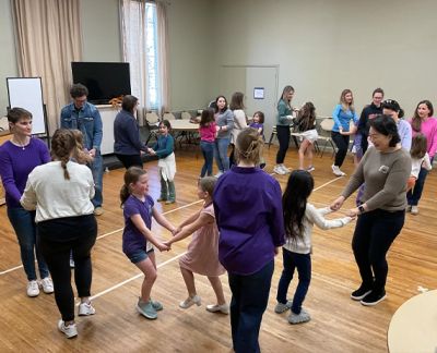 Singers and parents holding hands in a circle during a group activity