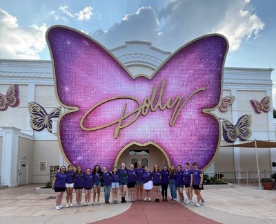 Singers lined up beneath the illuminated Dolly butterfly sign at Dollywood