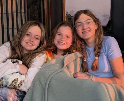 Three singers wrapped in a blanket together at sunset
