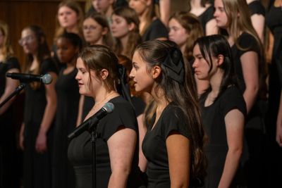 Two singers sharing microphones at the front of the choir
