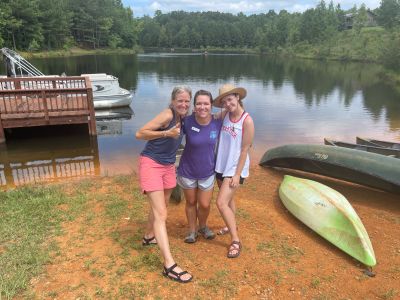 Three staff members posed by the canoes at the camp lake