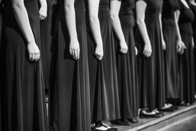 Detail of singers' hands and long concert gowns lined up in a row