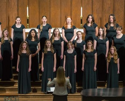 Singers mid-phrase with their director conducting in the foreground