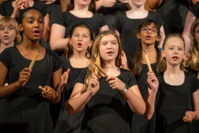 Young singers playing rhythm sticks as they sing