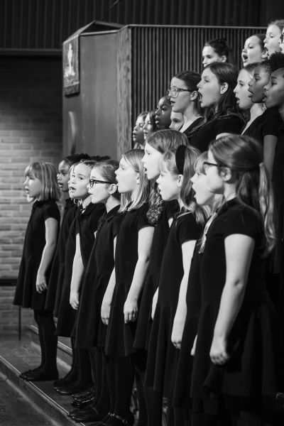 Black-and-white profile of the youngest choir lined up singing