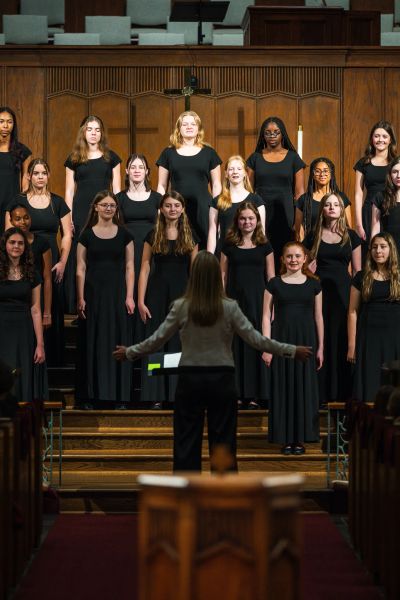 The choir on the chancel steps with the conductor's arms outstretched