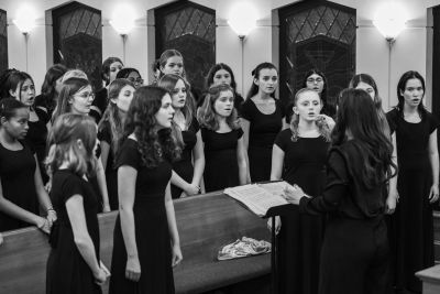 Black-and-white view of the older choir rehearsing with a director