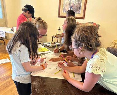 Singers working together on a drawing around a table