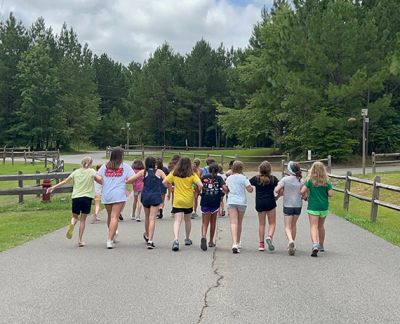 Singers walking arm in arm down a tree-lined road